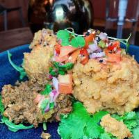 Mofongo · Mashed green plantains on a bed of mixed greens and topped with a salsa.