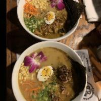 Curried Chicken Ramen · Noodles topped with curried chicken, scallions, carrots, corn, egg, edible flowers, sesame s...