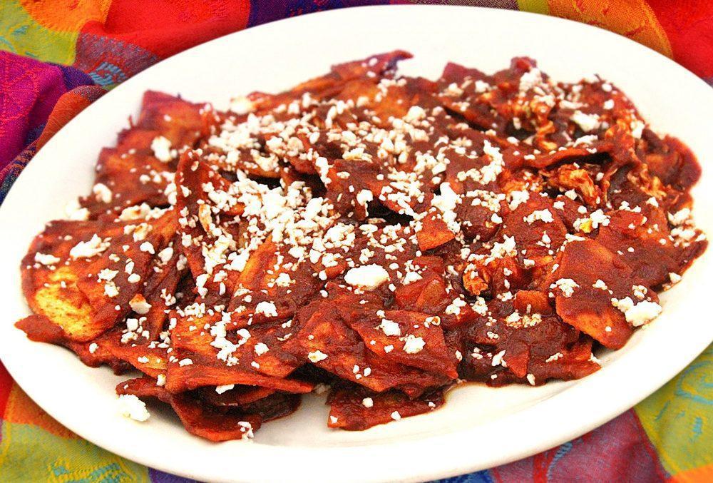 Chilaquiles · Corn chips simmered in green or red sauce until soft and topped with quesa fresco. Served with rice, beans, cheese & sour cream.