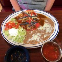 Stacked Enchiladas · 3 flat red corn tortillas loyered with charro beans, shredded cheese and your choice of grou...