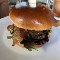 Tru Bistro Burger · Caramelized onions, goat cheese, bacon, mixed greens, balsamic reduction on a brioche bun.