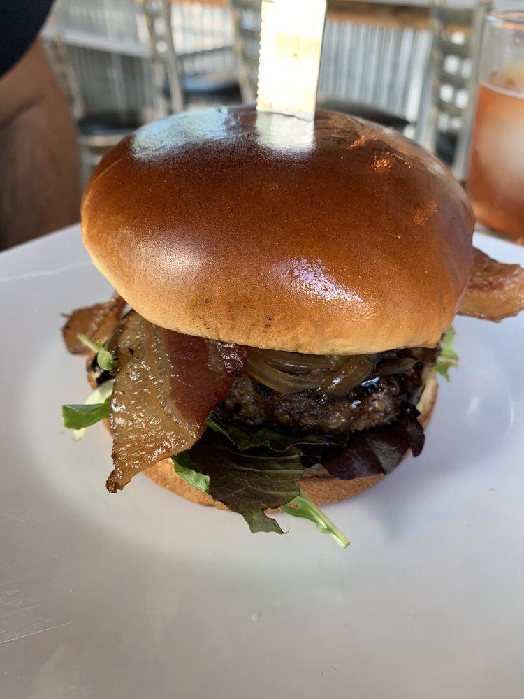 Tru Bistro Burger · Caramelized onions, goat cheese, bacon, mixed greens, balsamic reduction on a brioche bun.