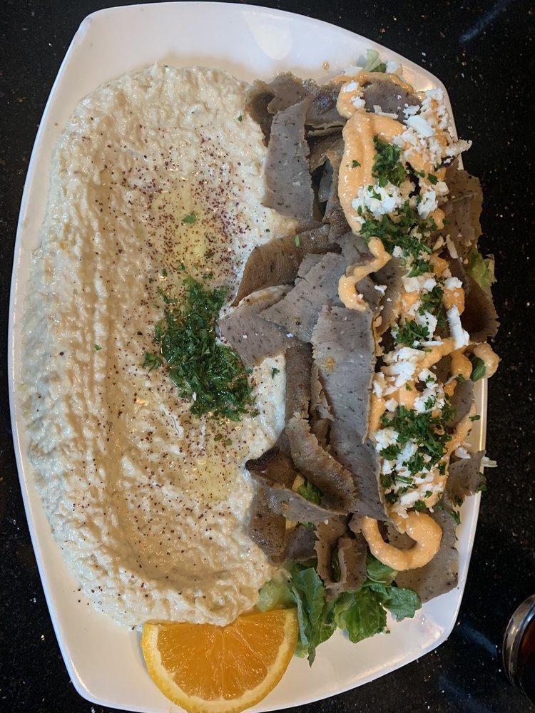 Baba Ghanouj · Smoky roasted eggplant with tahini. Garnish with olive oil and parsley. Served with fresh baked flatbread. Vegetarian. Gluten free.