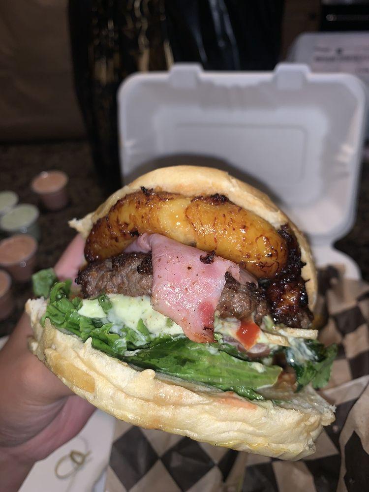 Tropical Burger · Meat, bacon, white cheese, ham, lettuce, tomato, crushed potato chips, fried sweet plantain, ketchup, pink sauce, mayonnaise and mustard.