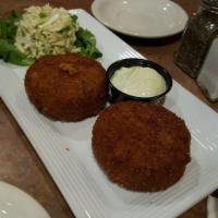 Crab Cakes · 2 thick homemade crab cakes served with serrano cream sauce and a side of cilantro lime slaw.