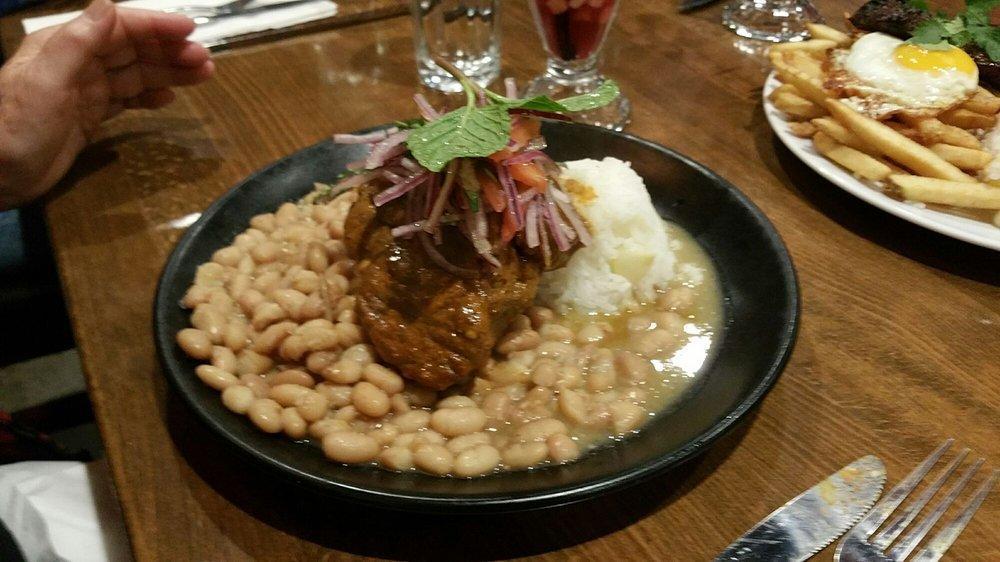Pork Adobo · Slow simmered pork shoulder in aji panca and spices, Peruvian rice, canary beans, served with a mint salsa criolla