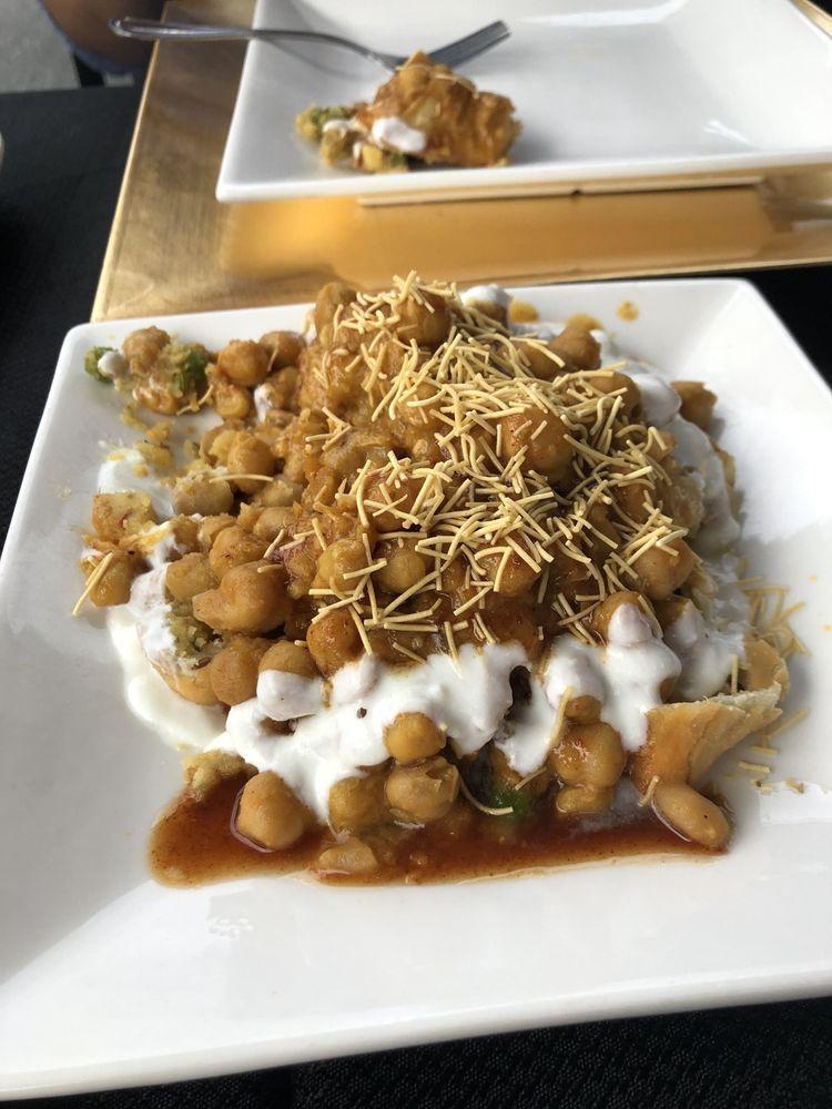 Papdi Chaat · A combination of crispy chips, chickpeas, onions and herbs seasoned in a spicy yogurt, mint chutney and tamarind chutney, covered with sev.