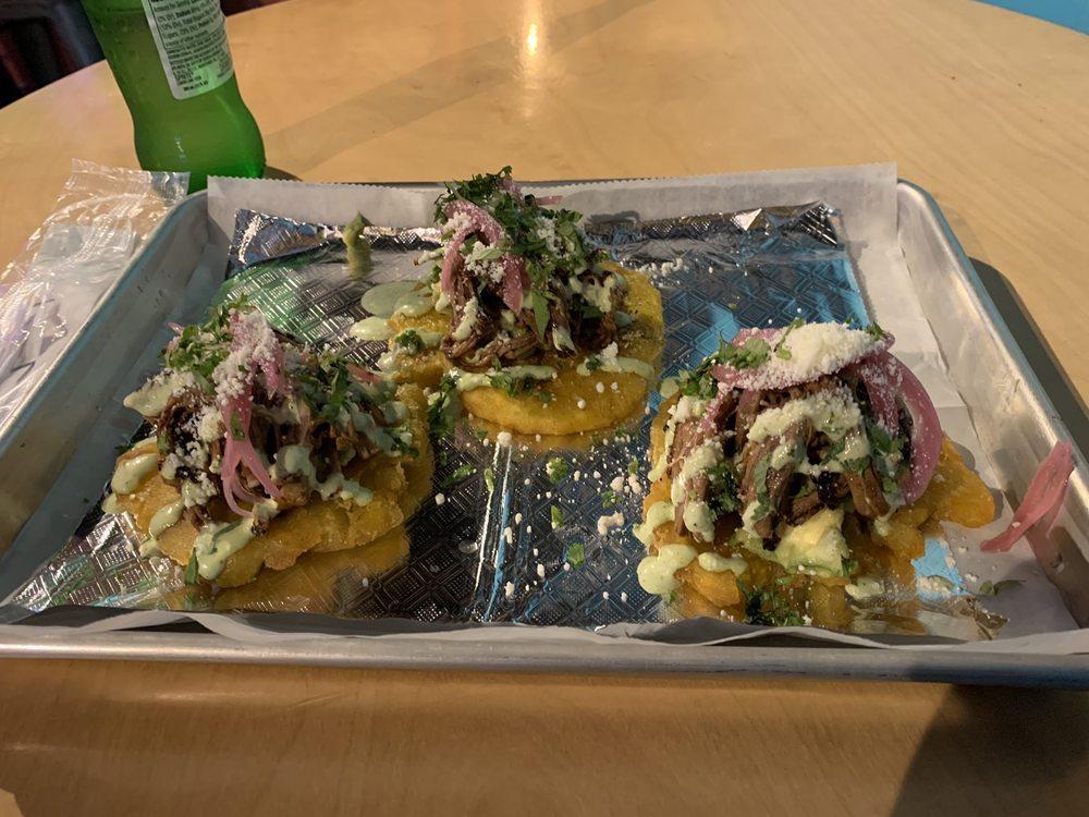 Tostones · 3 plantain tostones topped with ropa vieja (shredded beef), pickled onions, cotija cheese, guacamole and jalapeno aioli.