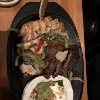 Fajitas · On a bed of caramelized onion and bell peppers. Garnished with roasted red pepper and cilant...