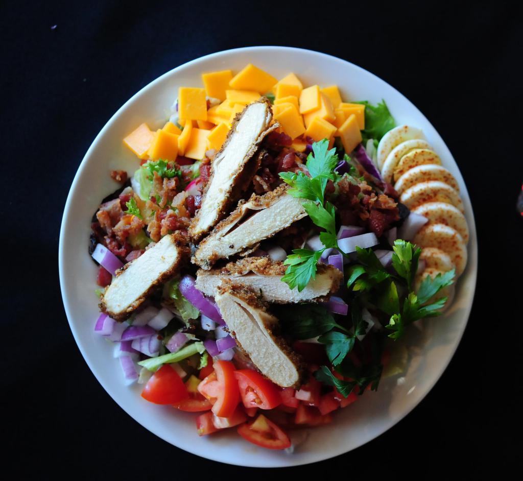 Chopped Cobb Salad Dinner · Breaded chicken, Roma tomatoes, bacon, eggs, red onions and cheddar cheese. Served with choice of dressing.