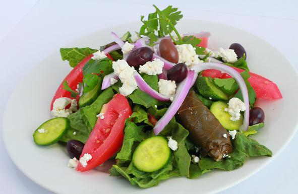 Greek Salad · Mixed greens, cucumbers, onions and tomatoes, topped with fresh feta cheese, black olives, peppers, stuffed grape leaves and feta dressing.