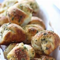 Famous Garlic Knots · Handmade garlic rolls topped with garlic oil, roasted garlic and Parmesan cheese.