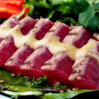 Seared Ahi Tuna Sashimi Salad · Fresh seasoned ahi tuna served over a bed of baby greens, with peppers, red onions, radish s...