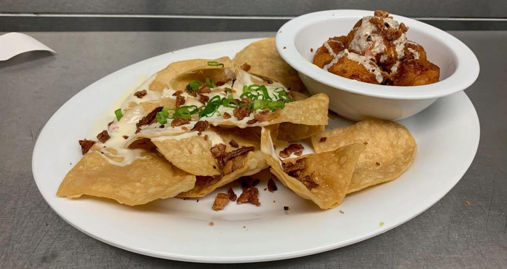 Mac N Cheese Bites · Six crispy golden bites filled with macaroni, American cheese, New York cheddar cheese and applewood smoked bacon. Topped with queso and bacon crumbles. Served with tortilla chips.