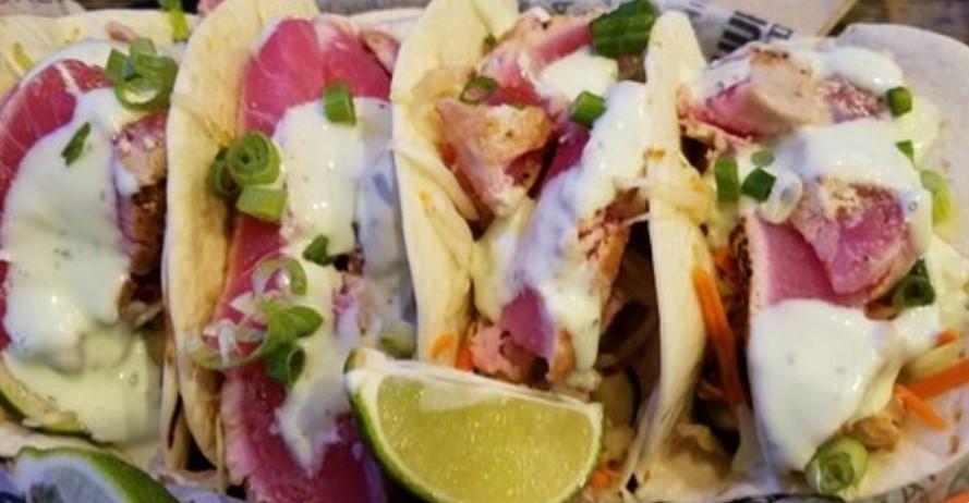 Ahi Tuna Tacos · Perfectly seared Ahi Tuna cooked medium rare served on top of an Asian slaw in two flour tortillas. Finished with a Cucumber Wasabi sauce and green onions.