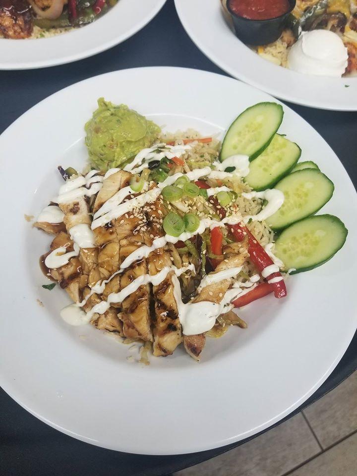 Thai Ginger Chicken Bowl · Sweet and spicy pineapple marinated chicken breast served over Cilantro Lime Rice with crisp bell peppers and cabbage tossed in a ginger sauce. Topped with cucumber and fresh guacamole garnished with toasted sesame seeds, green onions and lime crema.