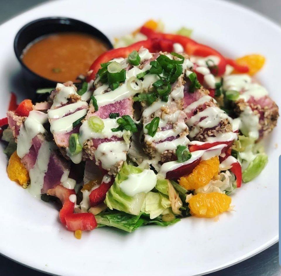 Seared Ahi Tuna Salad · Mixed greens tossed in a Mandarin Ginger dressing, topped with seared Ahi Tuna medallions, Asian slaw, mandarin orange segments and red pepper slices. Finished with a drizzle of a Cucumber Wasabi sauce and green onions.