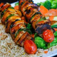 Skewered Teriyaki Chicken Kebab · Teriyaki marinated chicken kebabs with peppers & onions served over brown rice, steamed vege...