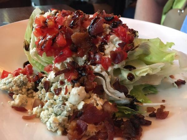 Iceberg Wedge Salad · Creamy blue cheese dressing, crispy bacon, blue cheese crumbles, Romano cheese, tomatoes and balsamic reduction.