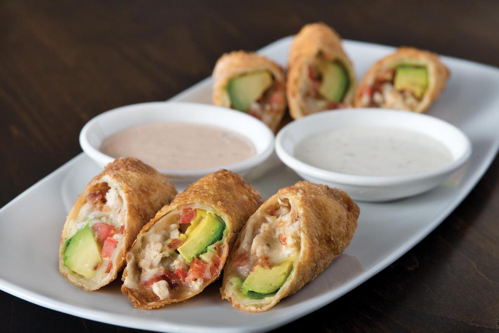 Avocado Club Egg Rolls · Hand-wrapped crispy wonton rolls filled with avocado, chicken, tomato, Monterey Jack and Nueske's Applewood smoked bacon. Served with housemade ranchito sauce and herb ranch.