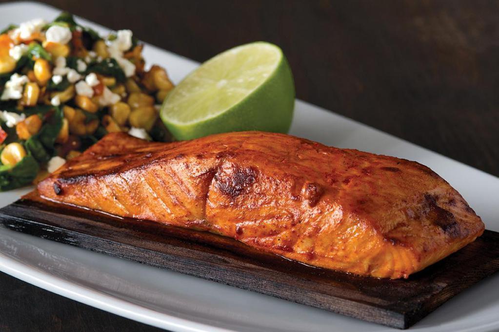 Cedar Plank Salmon · North Atlantic salmon roasted on a cedar plank in our hearth oven with smoked paprika and lime. Served with white corn and spinach succotash and topped with feta. Gluten-free ingredients. 
