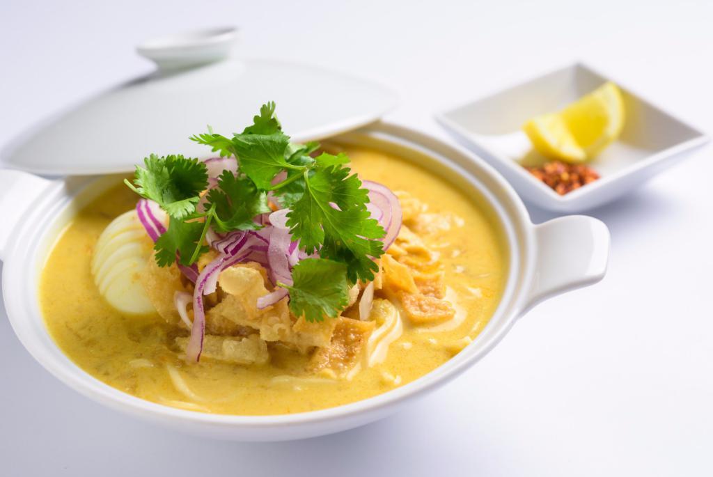 Ohnoh Kawt Swe · Coconut Noodle Soup. A rich and creamy coconut bisque with flour noodles. Served with chicken, onion, tamarind powder and paprika. Garnished with onion, cilantro and lemon.

