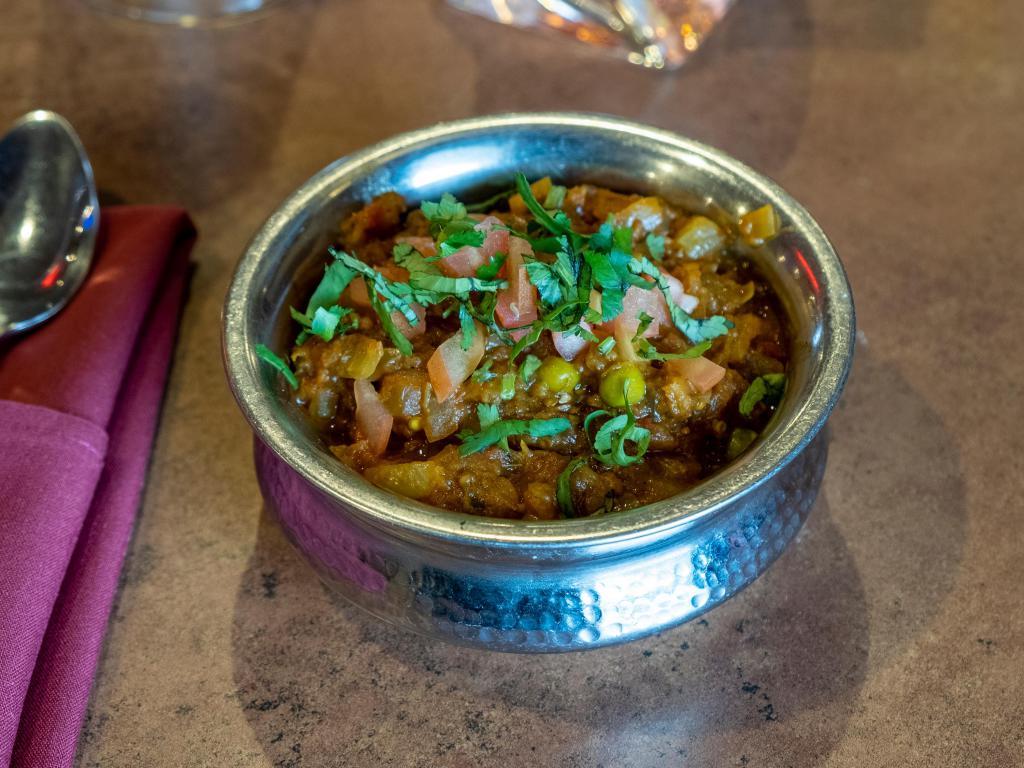 Baigan Bhartha · Eggplant roasted in the tandoor and cooked with green peas, fresh tomatoes, onion, ginger and garlic. Vegetarian.