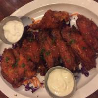 Buffalo Chicken Wings · Chicken wings tossed in traditional buffalo sauce, topped with scallions with ranch on the s...