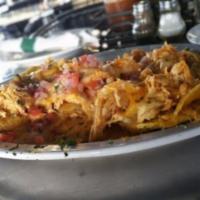 Patacon con Pollo · Fried green plantains layered with chicken fricassee, melted cheese, topped with fresh tomat...