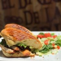 Sandwich de Pollo a la Plancha · Grilled chicken breast topped with caramelized onions, tomatoes, and Swiss cheese, pressed o...