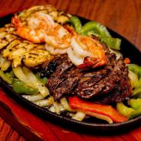 Combo Fajitas · Marinated sizzling strips of steak, chicken and shrimp, topped with sauteed onions and green...