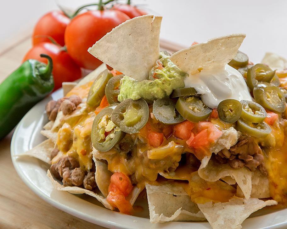 Nacho Supreme · Tostada chips, slow cooked beans, queso sauce, jalapenos, guacamole, sour cream and tomato. 1380 calories.