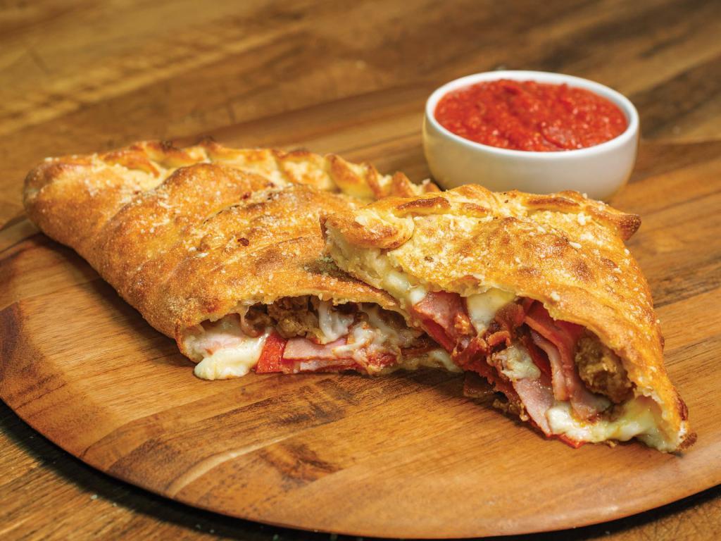 All Meat Calzone · Stuffed with pepperoni, ham, Italian sausage, bacon and our signature 3 cheeses, served with a side of our original pizza sauce.