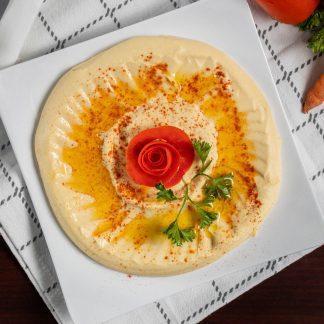 Hummus · A tasty mix of garbanzo beans with a touch of garlic, lemon juice and tahini sauce, topped with olive oil and served with warm pita bread.