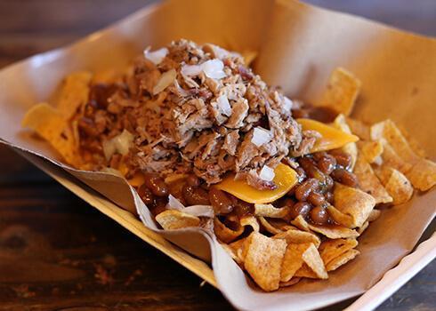Fritos Pie Stack · Corn chips with your choice of barbecue beans or jalapeno beans and your choice of chopped beef brisket or pulled pork, topped with cheddar cheese and white onions, sprinkled with rib rub