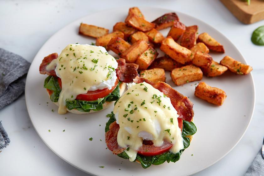 Florentine Benedict · Bacon, poached eggs, spinach and sliced tomatoes topped with hollandaise sauce on a grilled English muffin.