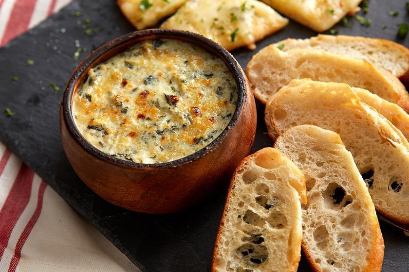 Spinach Artichoke Dip · Deliciously rich, perfectly creamy and cheesy with spinach and artichokes baked to perfection. Served with sliced bread!