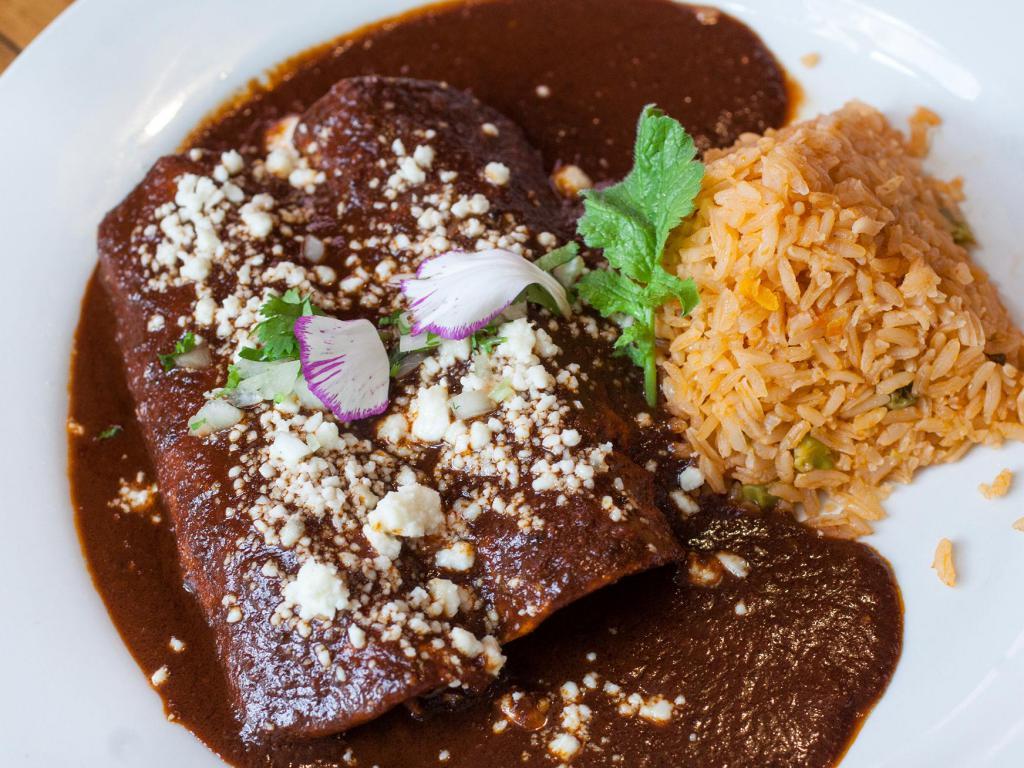 Enchiladas de Mole · Simmered in signature mole poblano sauce, 2 corn tortillas  filled with your choice of chicken, carnitas or vegetables, lightly garnished with pickled red onion, toasted sesame seeds and queso fresco.
