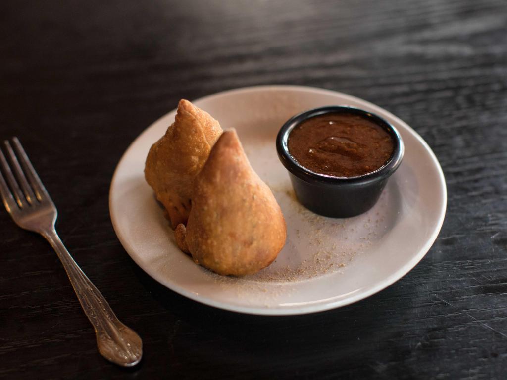 Vegetable Samosa · 2 samosas filled with spiced potato, cabbage, green onion, peas wrapped in a thin layer of flour dough and fried crisp. Served with tamarind sauce. Vegan.