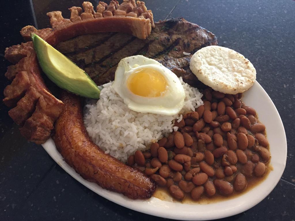 27. Bandeja Montanera · Country platter. Rice, beans, grilled steak, pork skin, fried egg, avocado, sweet plantain and corn cake.