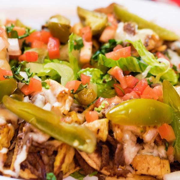 Nachos DLX · Crispy corn tortillas coated with refried beans and melted Monterrey cheese. Served with romaine lettuce, pico de gallo and jalapenos. With choice of meat or grilled veggies.