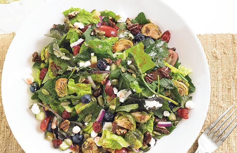 Kale And Roasted Brussels Sprouts Salad · Baby kale, roasted brussels sprouts, romaine, fresh blueberries, sweet red grapes, dried cranberries, goat cheese, cucumbers, candied pecans, toasted pepitas, red onions, strawberry vinaigrette