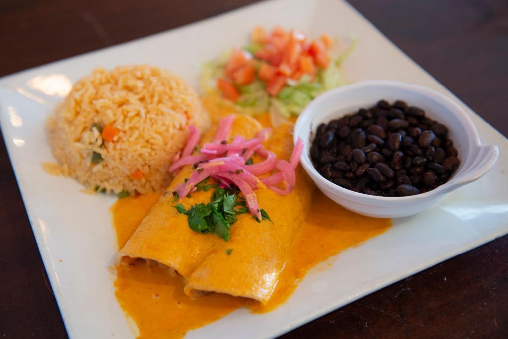 Enchiladas En Salsa de Habanero · 2 hand-made corn tortillas filled with chicken carnitas, finished with a delicious roasted habanero-cream sauce. Served with rice, black beans, pickled red onions and cilantro garnish.