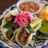 Tacos de la Calle · Corn tortillas filled with pork carnitas or asada, cilantro, pickled red onions, and lime. S...