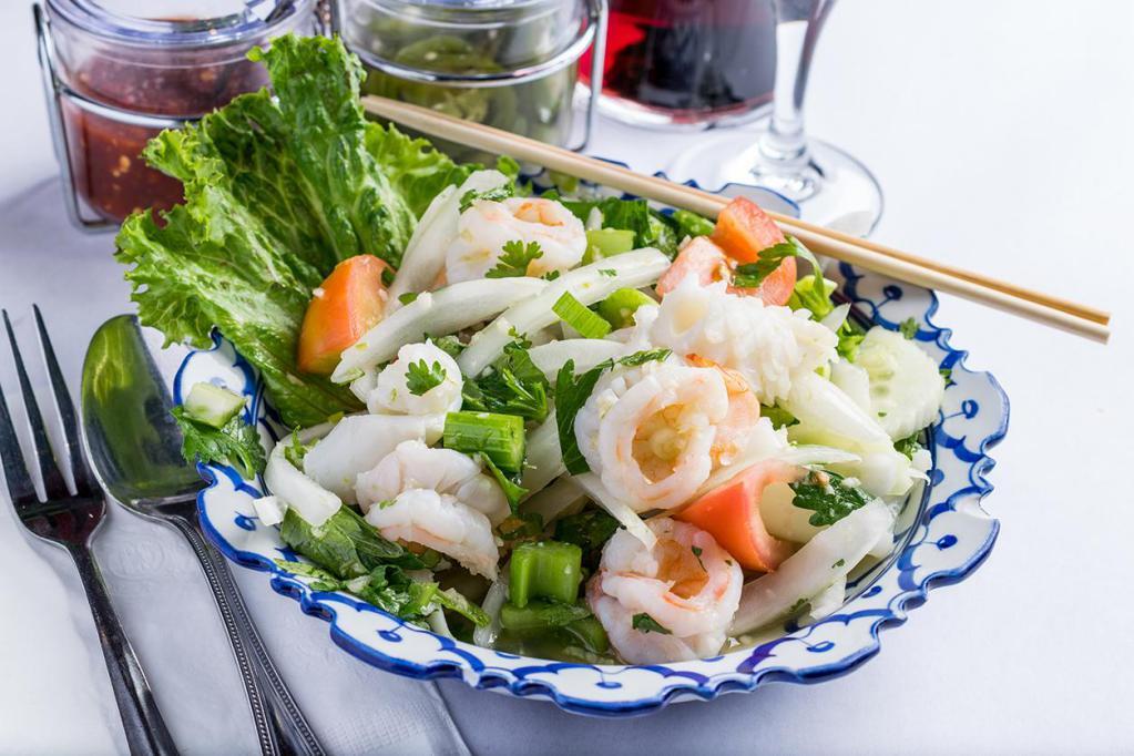 Seafood Medley Salad · Combination of prawns, calamari layered in with fresh cucumber, onions, tomatoes, celery, cilantro and drizzled with lime juice and fish sauce.