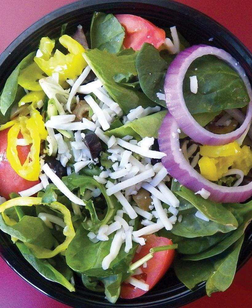 Italian Salad · The perfect salad for pairing with pizza! Our Italian salad is a bed of spring mix, romaine, and iceberg lettuce, dressed with red onion rings, black and green olives, fresh quartered tomato wedges, pepperoncini peppers, and mozzarella cheese. Comes with creamy Italian dressing on the side.