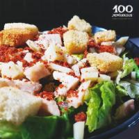 Caesar Salad · Romaine lettuce, chicken, Serrano bites, Manchego cheese, croutons, and Caesar dressing.