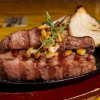 Picanha na Chapa · Grilled top sirloin steak served sizzling with rice, beans, roasted yucca flour and vinaigre...