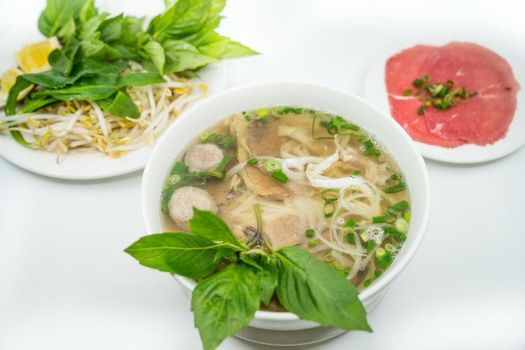 1. Large Combination Pho · Vietnamese pho noodle soup served with steak, well done brisket, beef ball, tendon, and tripe - rice noodle, garnished with green and white onion.