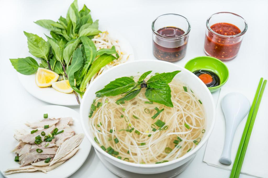 12. Large Chicken Pho Noodle Soup · Vietnamese pho noodle soup served with chicken, rice noodle, garnished with green and white onion.
